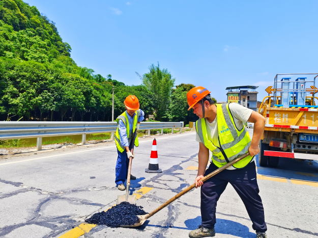 图为养护人员在修补路面坑槽(温忠摄).png
